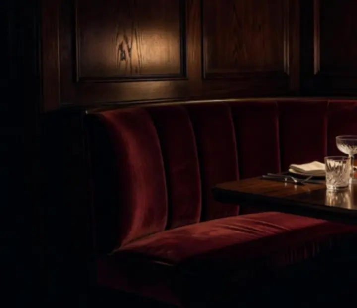 Intimate velvet-lined private dining booth with candlelit table in a speakeasy